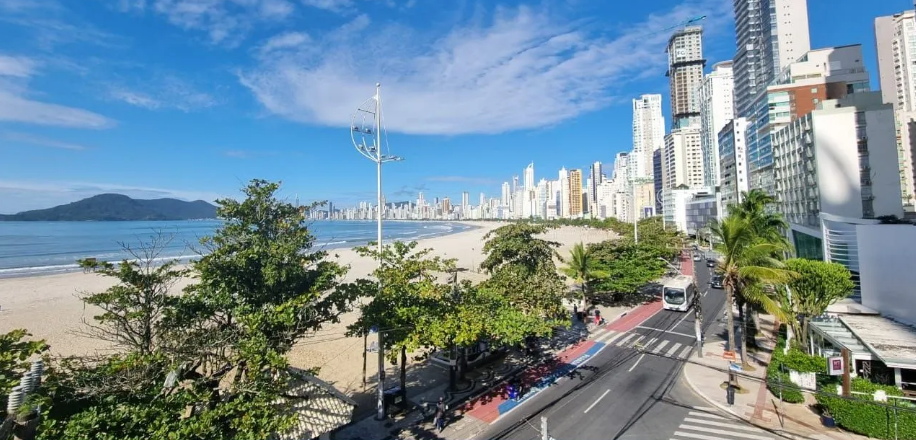 Vista noturna de um edifício Marama iluminado e uma roda-gigante vermelha ao lado de uma rua com pedestres e carros.
