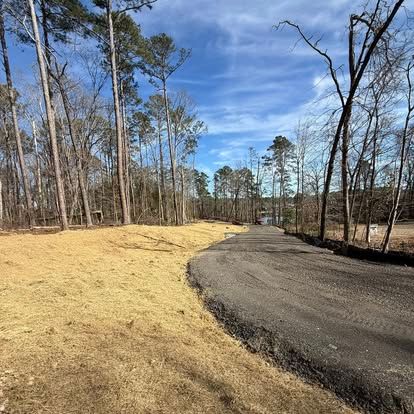 Curving gravel path beside a grassy area and bare trees under a clear blue sky