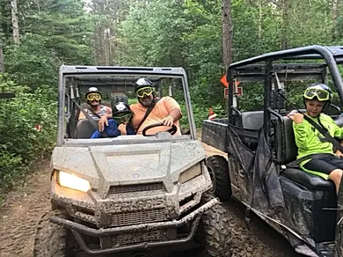 A group of people are riding atvs through the woods.