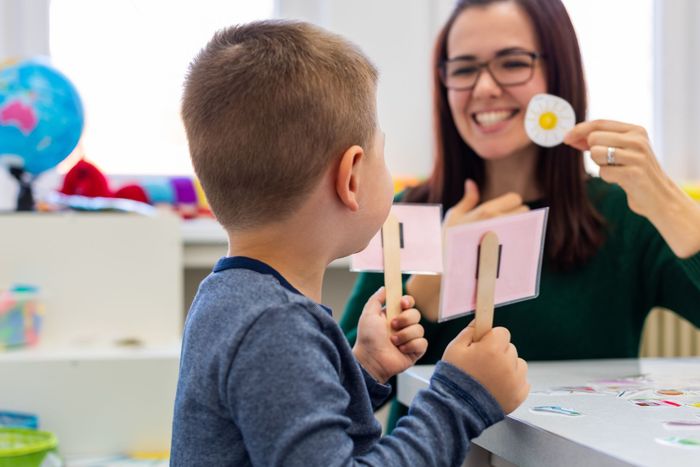 Teacher showing a craft to a child in a classroom, both smiling
