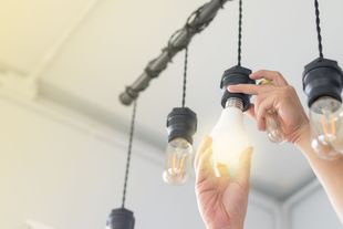 A person is changing a light bulb in a chandelier.