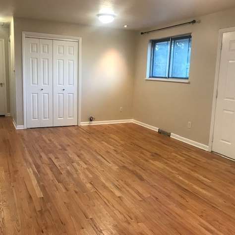 Empty room with hardwood floors, white doors, and a small window.