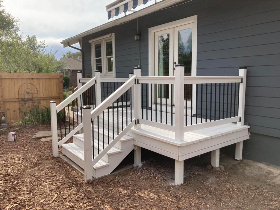 White deck with black railing, steps, and gray house.