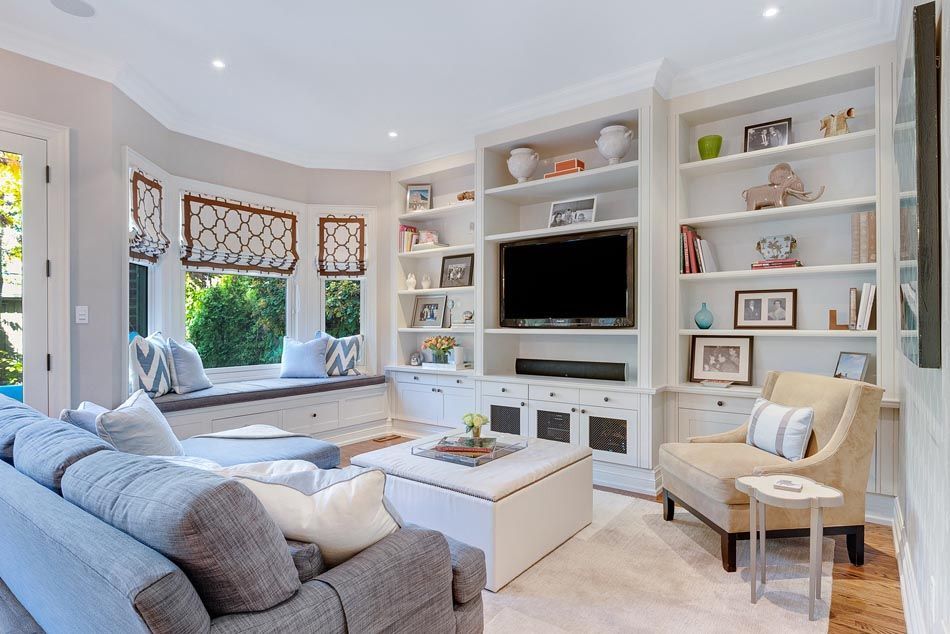 Living room with built-in bookshelves, bay window seat, gray sofa, armchair, and white coffee table.