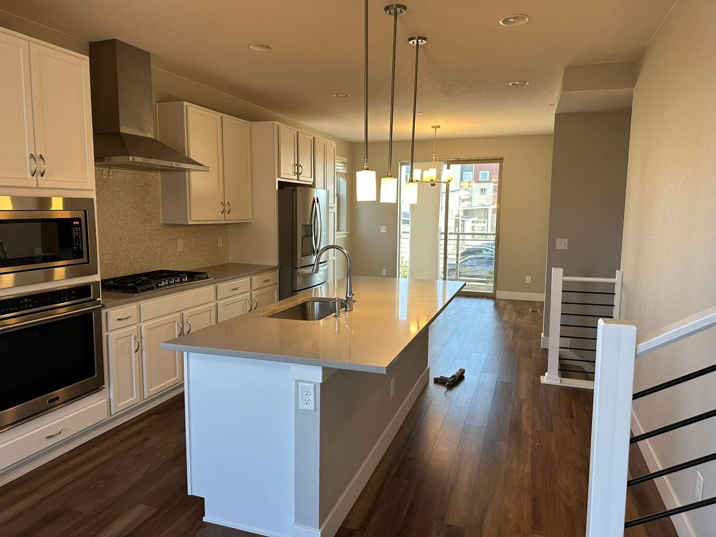 Modern kitchen with white cabinets, stainless steel appliances, island, and wood floors.