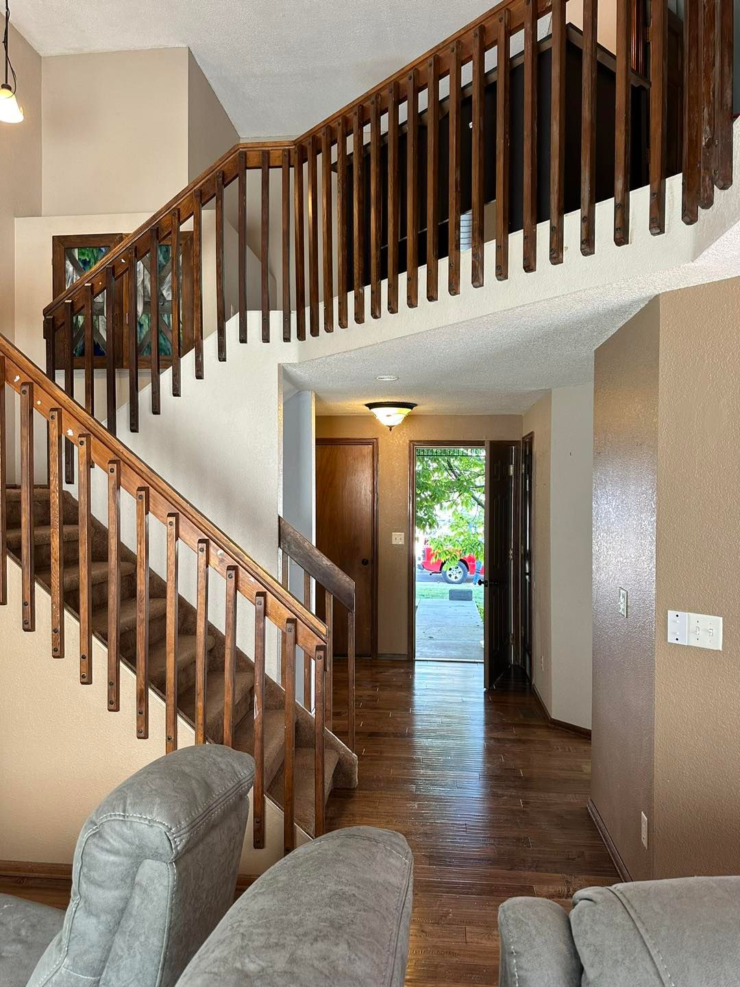 Two-story home foyer with curved wooden staircase, hallway, and view of front door and garden.