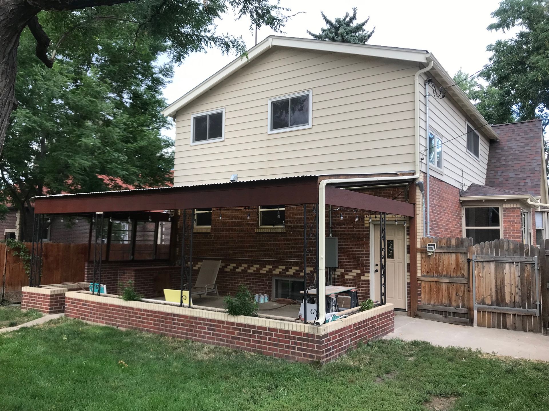 Two-story house with a brick patio, covered deck, and a fenced yard.