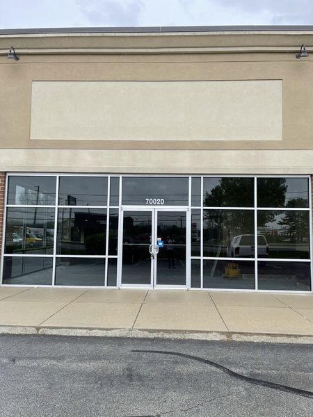 Empty storefront with glass doors and windows beneath a blank beige sign.
