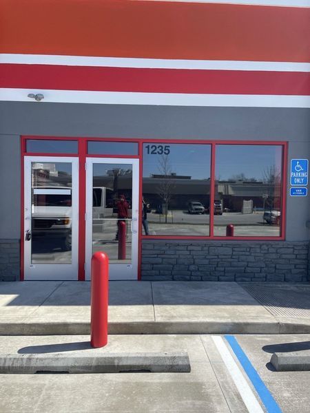 Storefront with red trim, glass windows, accessible parking, and address 1235 above the entrance.