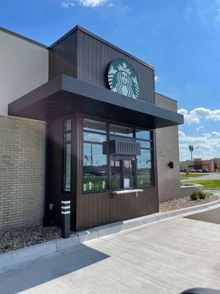 Starbucks drive-thru window on a brick storefront under a blue sky