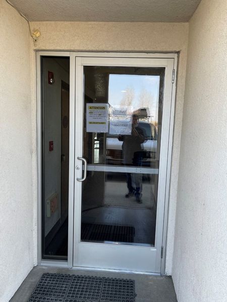 Glass entrance door with notice sign, viewed from a covered walkway