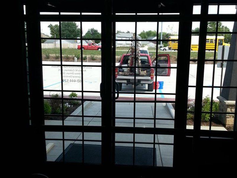 Red utility vehicle parked outside behind a window with metal bars and glass panes