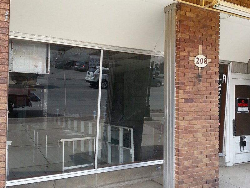 Closed storefront with large windows and a brick entrance marked 208