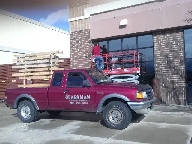 Maroon pickup truck parked outside a building with a red lift in the background