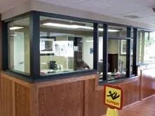 Wood-paneled lobby security booth with glass windows and a yellow caution sign nearby