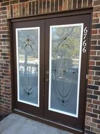 Dark brown double front door with frosted glass panels and house number 6766 beside it