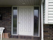 White front door with sidelights on a brick house porch