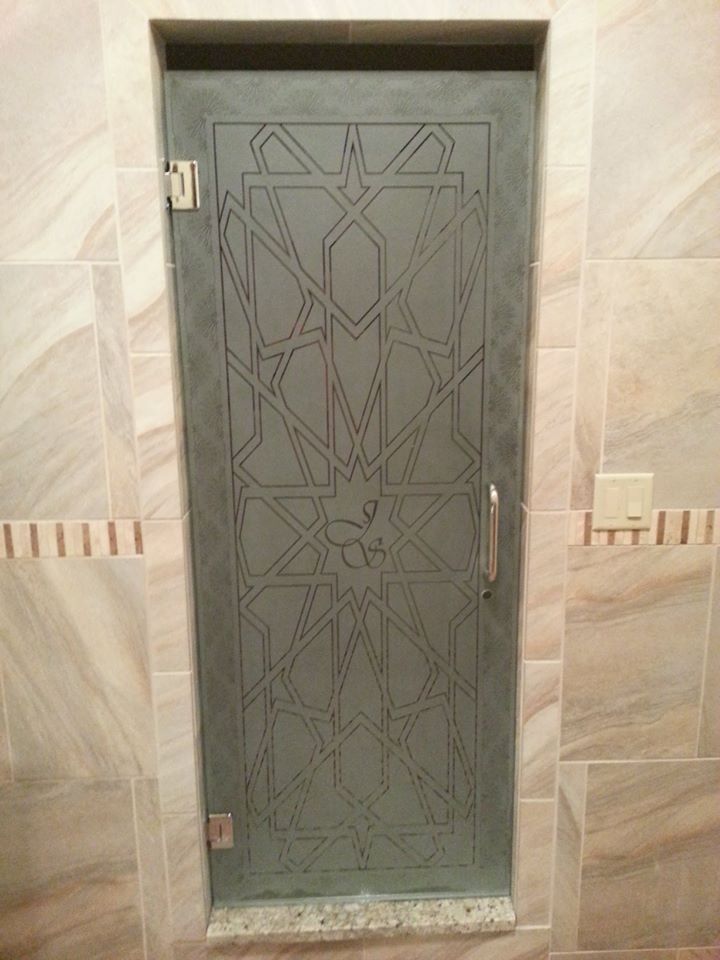 Gray metal door with geometric patterns set in a beige tiled wall