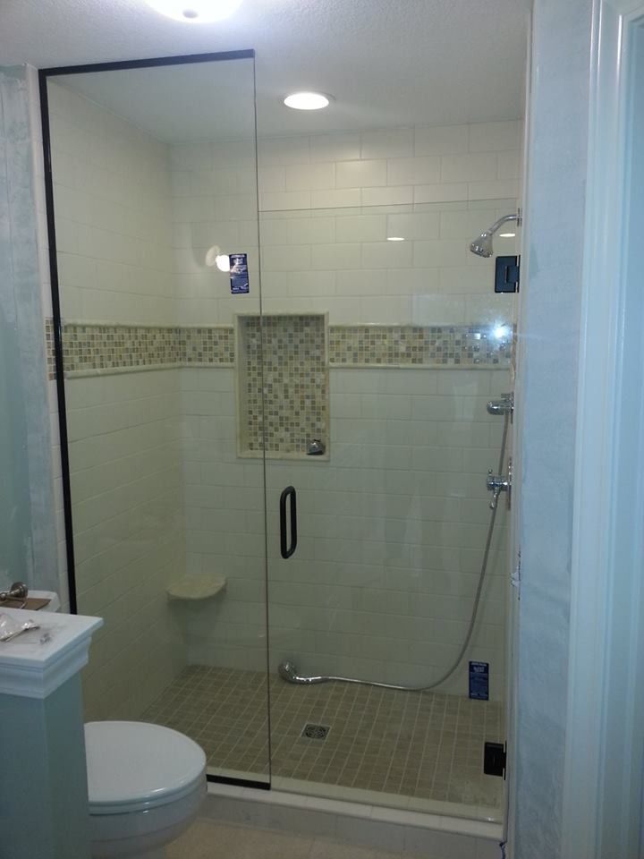 Accessible bathroom with glass-enclosed shower, grab bars, and tiled walls