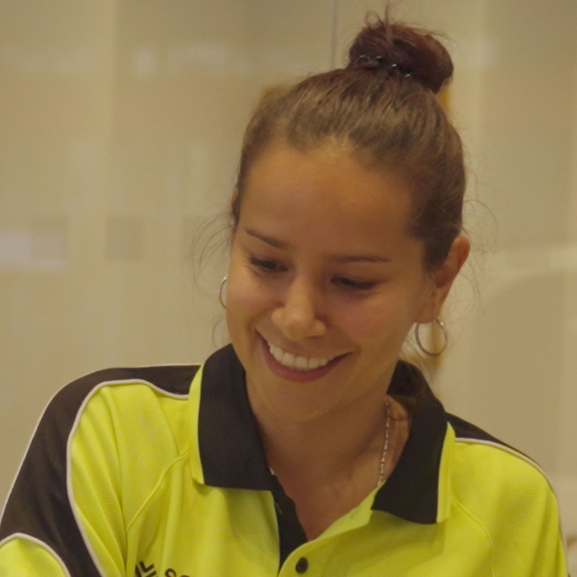 A smiling woman in a yellow shirt holds a piece of paper, representing a positive moment at SSX Group.