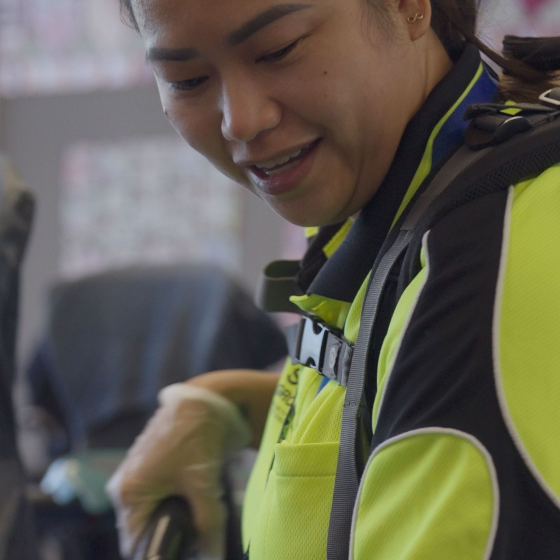 A woman in a yellow shirt and black gloves, representing SSX Group Security, stands confidently.