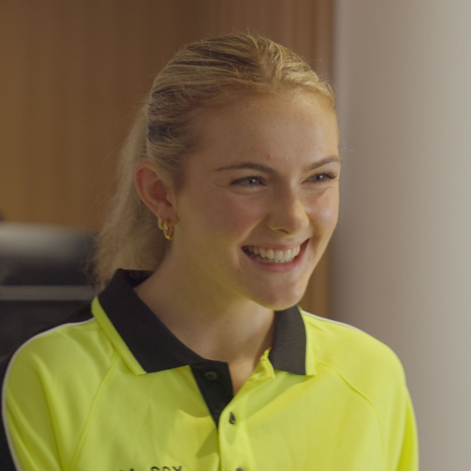 SSX Group Security woman with a cheerful expression, wearing a yellow shirt.