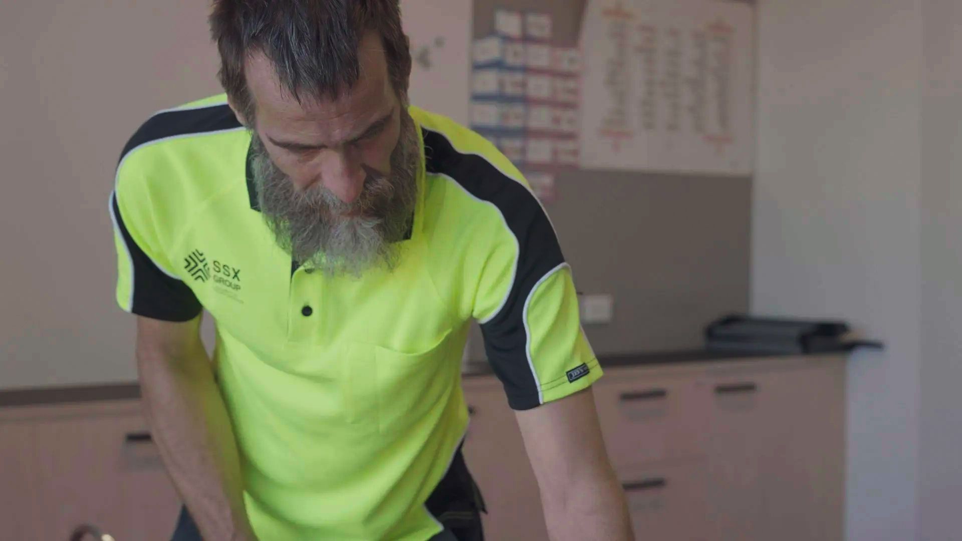 A man wearing a high-visibility work uniform featuring the logo of SSX