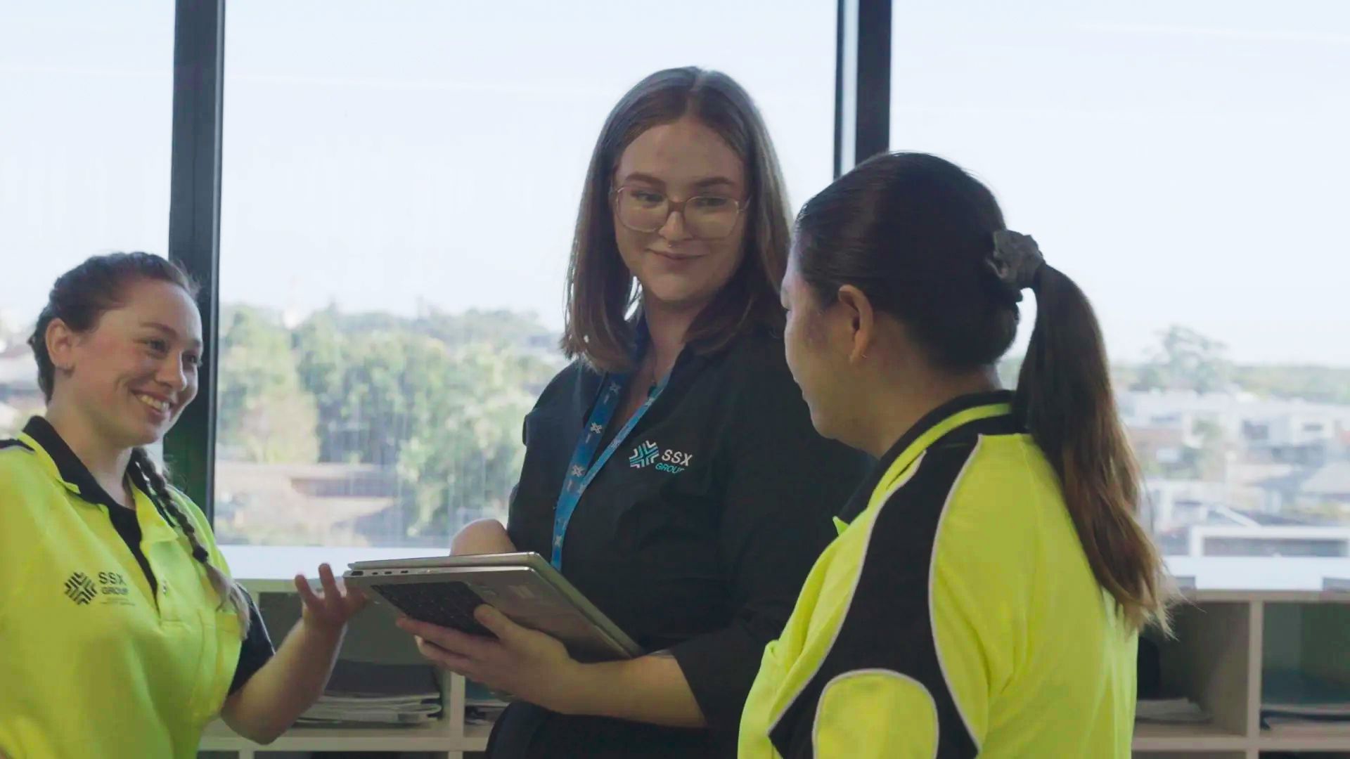 Three individuals of SSX Group having a professional conversation in an office setting.