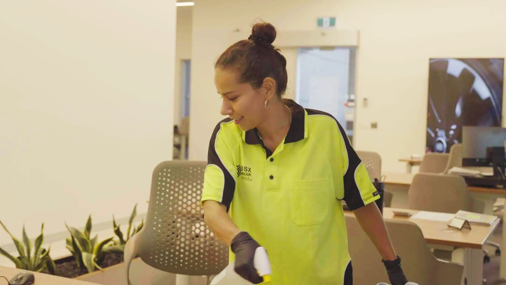 Commercial cleaner cleaning an office desk. 