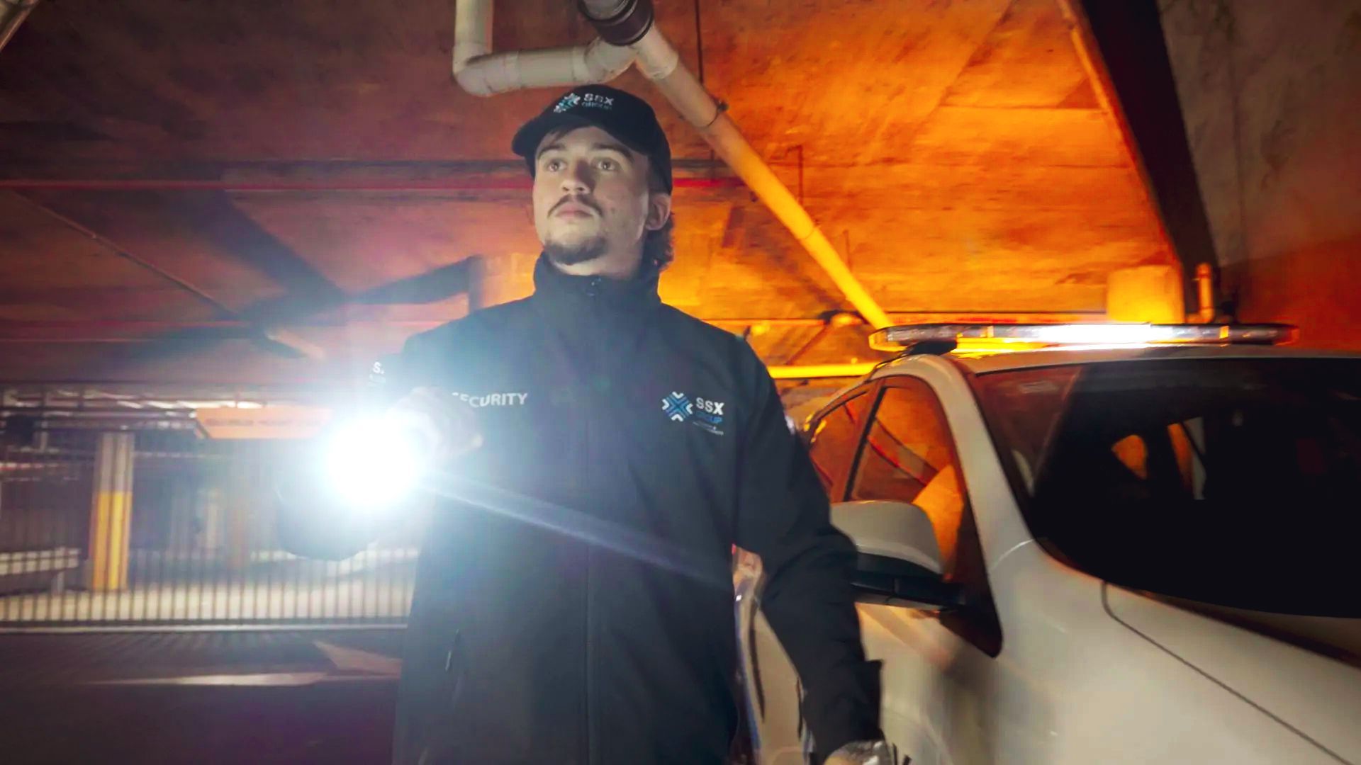 A SSX group security guard patrolling a parking garage at night.
