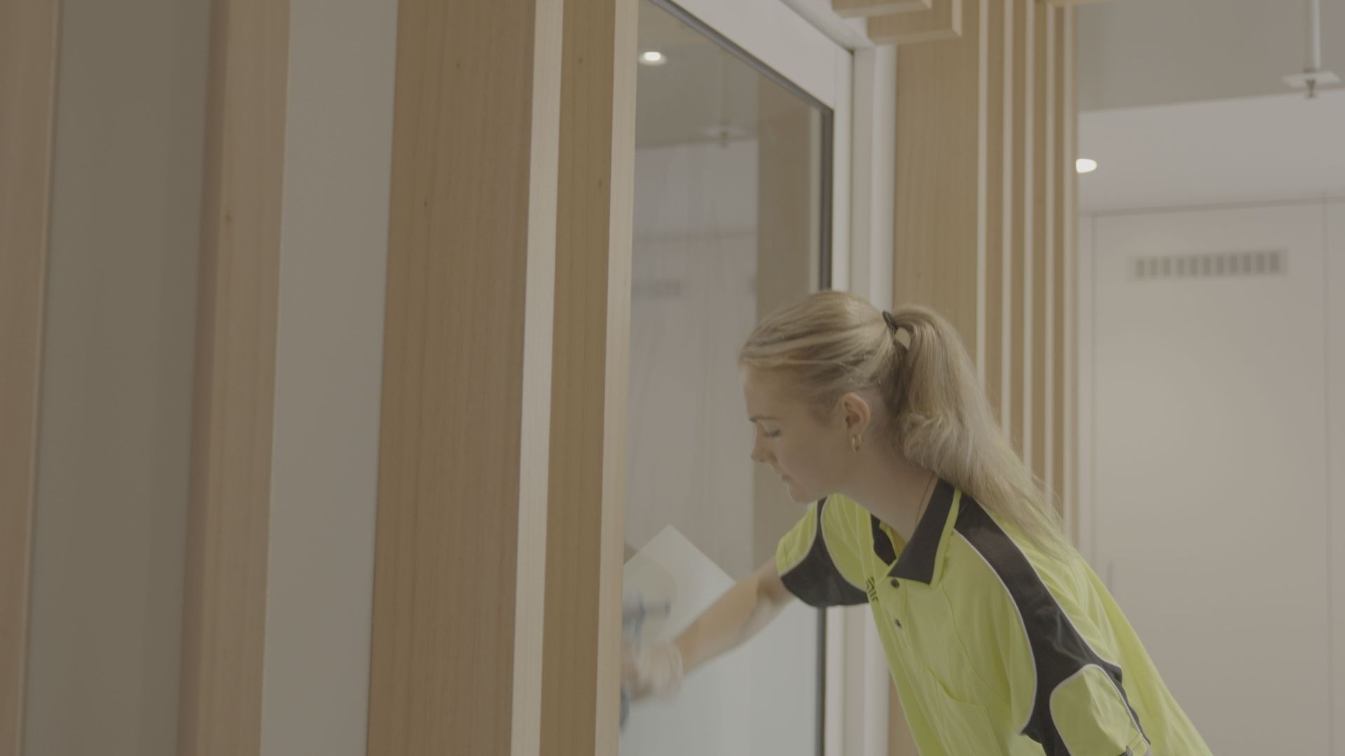 A SSX group woman is cleaning a glass door with a cloth.