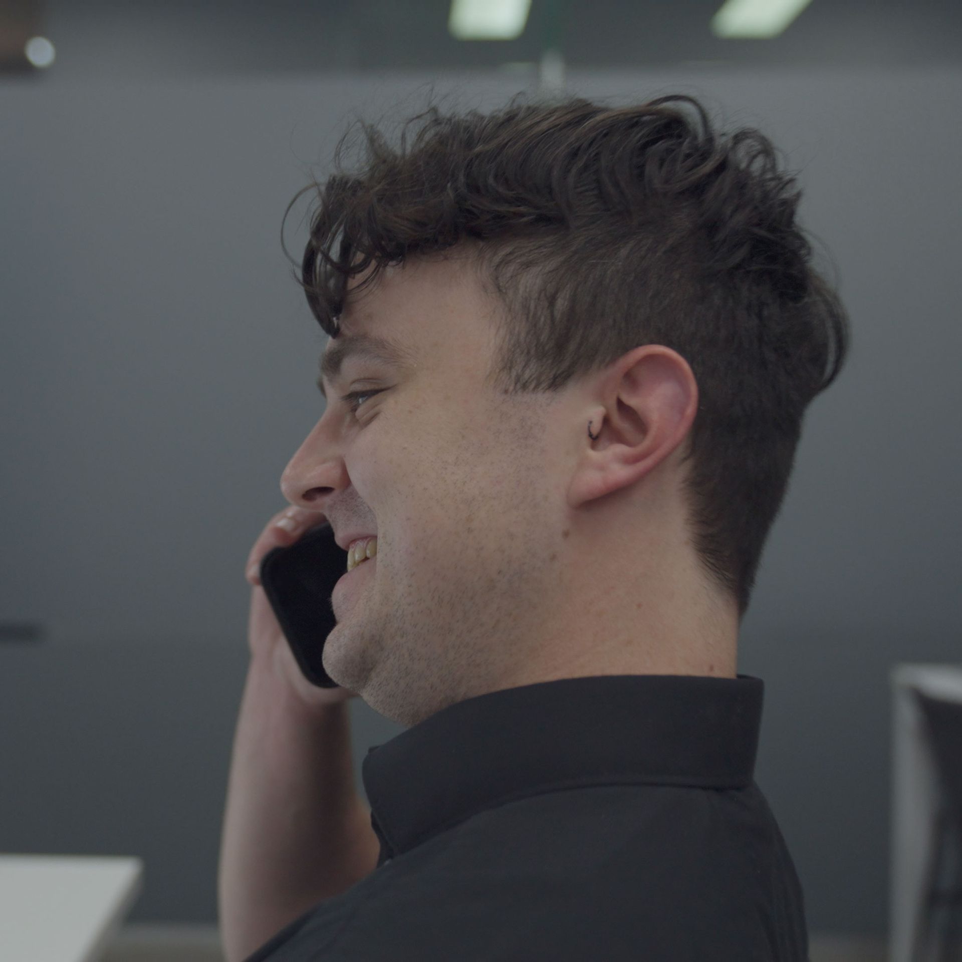 A man in a black shirt is talking on a cell phone