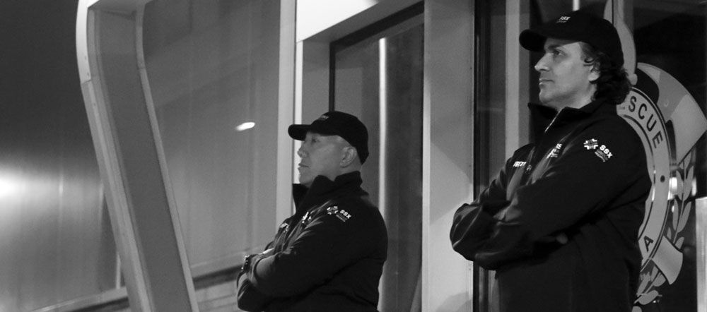Two security guards are standing next to each other in front of a building.