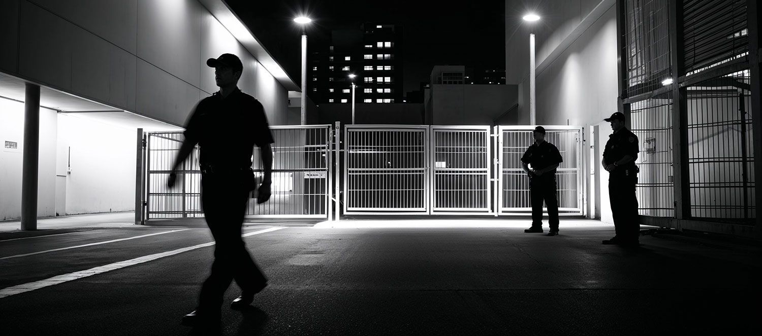 A man walking alone in a dark alley at night, highlighting the need for security and vigilance in urban areas.