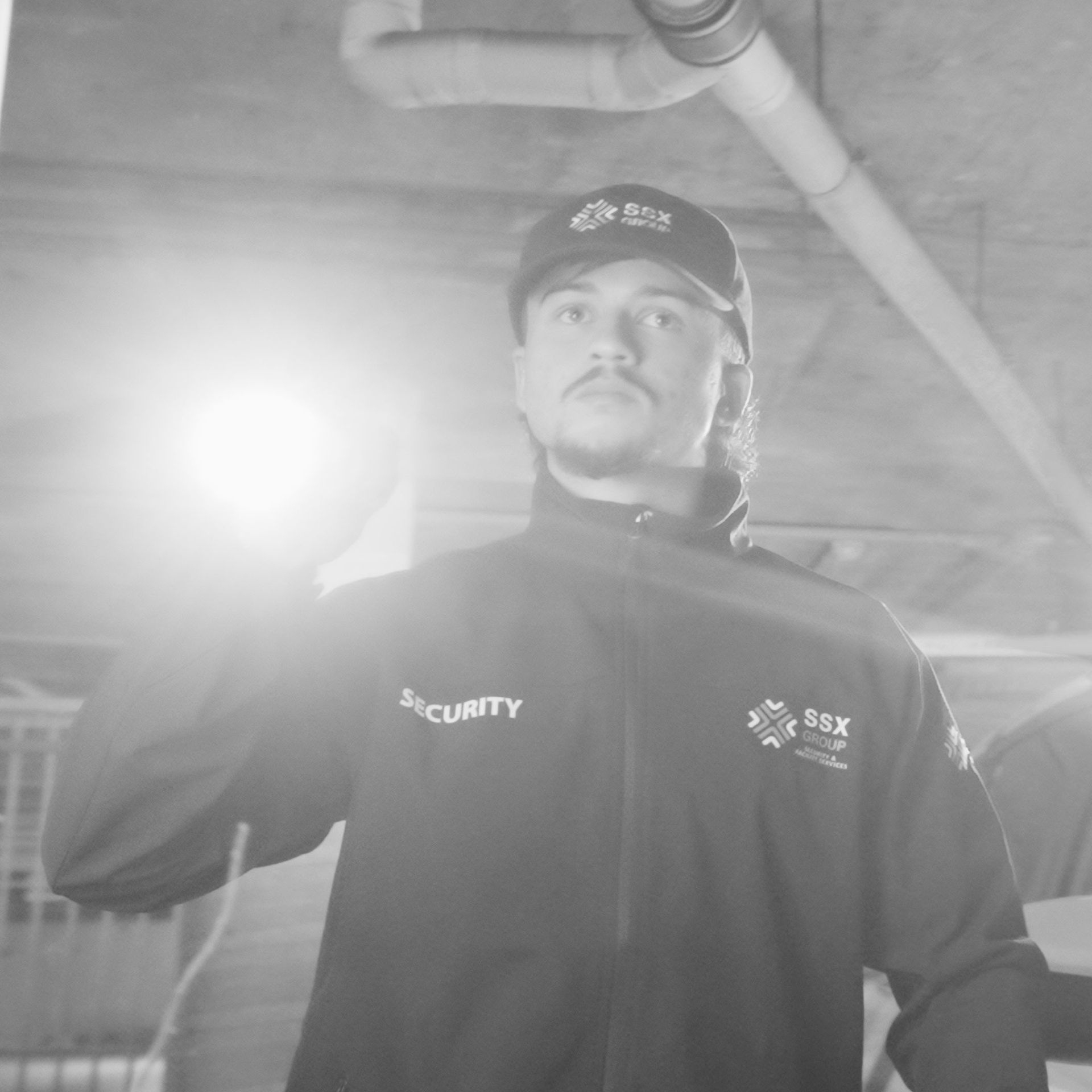 A black and white photo of a man wearing a security jacket