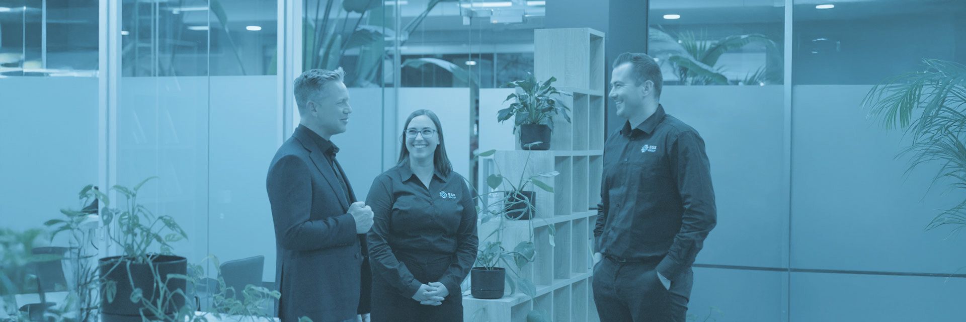 SSX group team members in an office, standing together and discussing work-related topics.