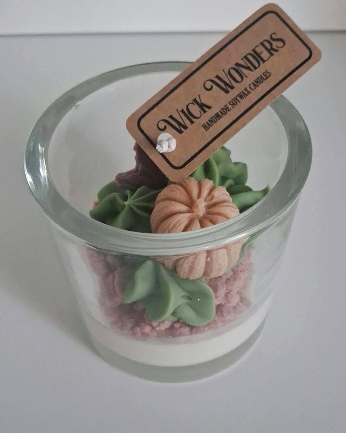 Kaars in een glazen pot met roze kruimellaag en herfstblaadjes
