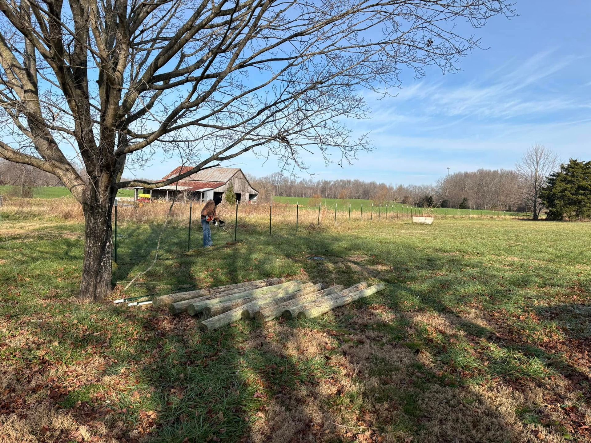 A man is standing in a field with a barn in the background.