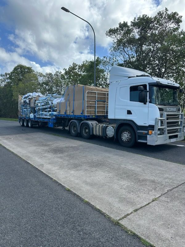 White Truck Hauling a Flatbed Trailer Loaded — Alfie's Towing in Bentley Park, QLD