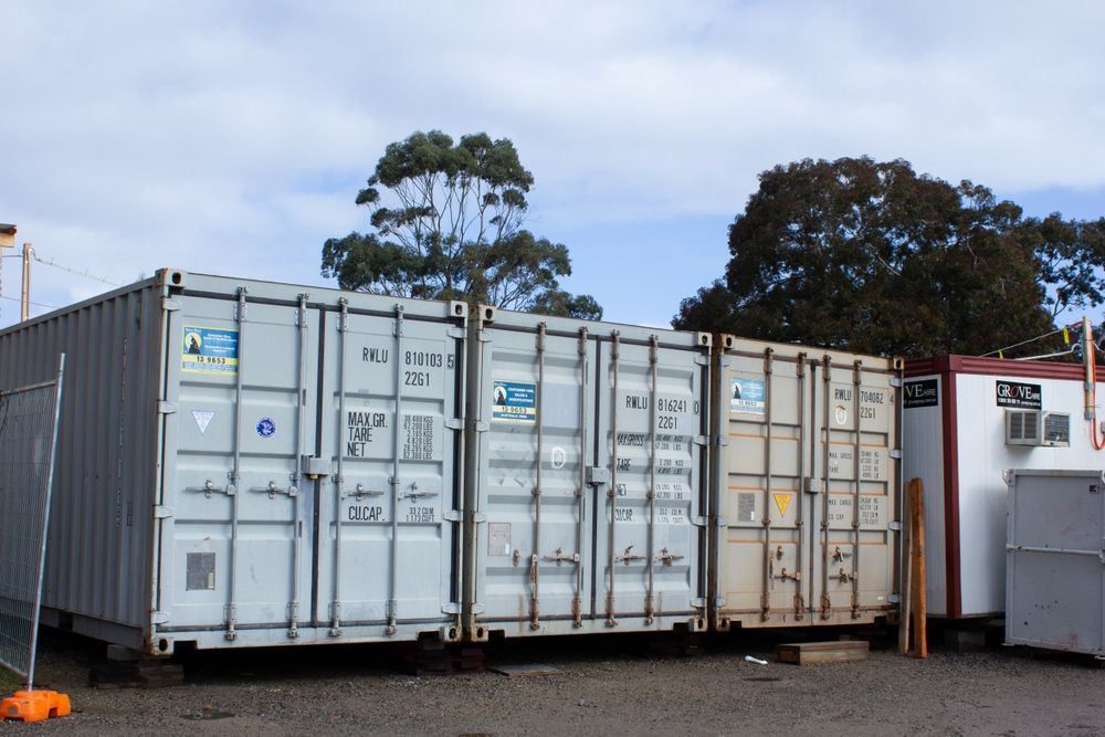 Shipping containers lined up outdoors, in shades of gray and tan — Alfie's Towing in Bentley Park, QLD