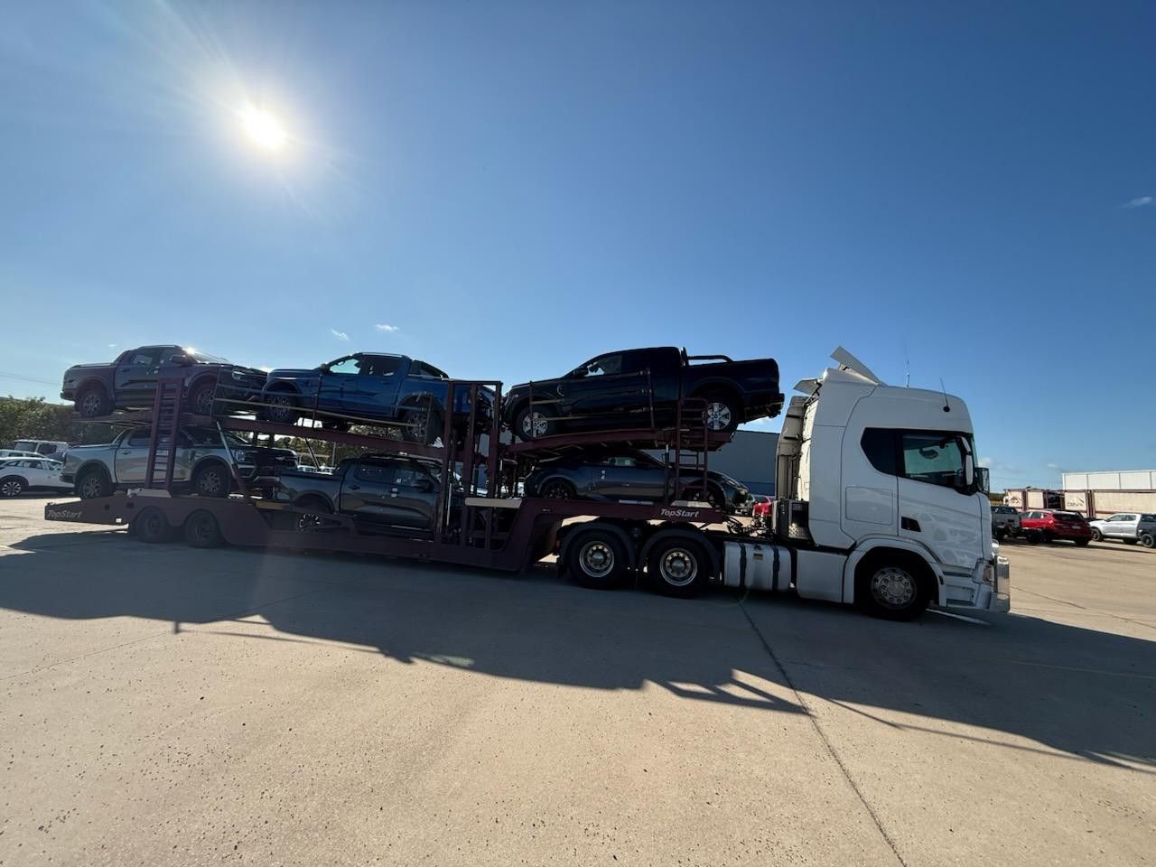 A Car Carrier Truck Transporting Several Pickup Trucks Under a Bright Blue Sky — Alfie's Towing in Weipa, QLD