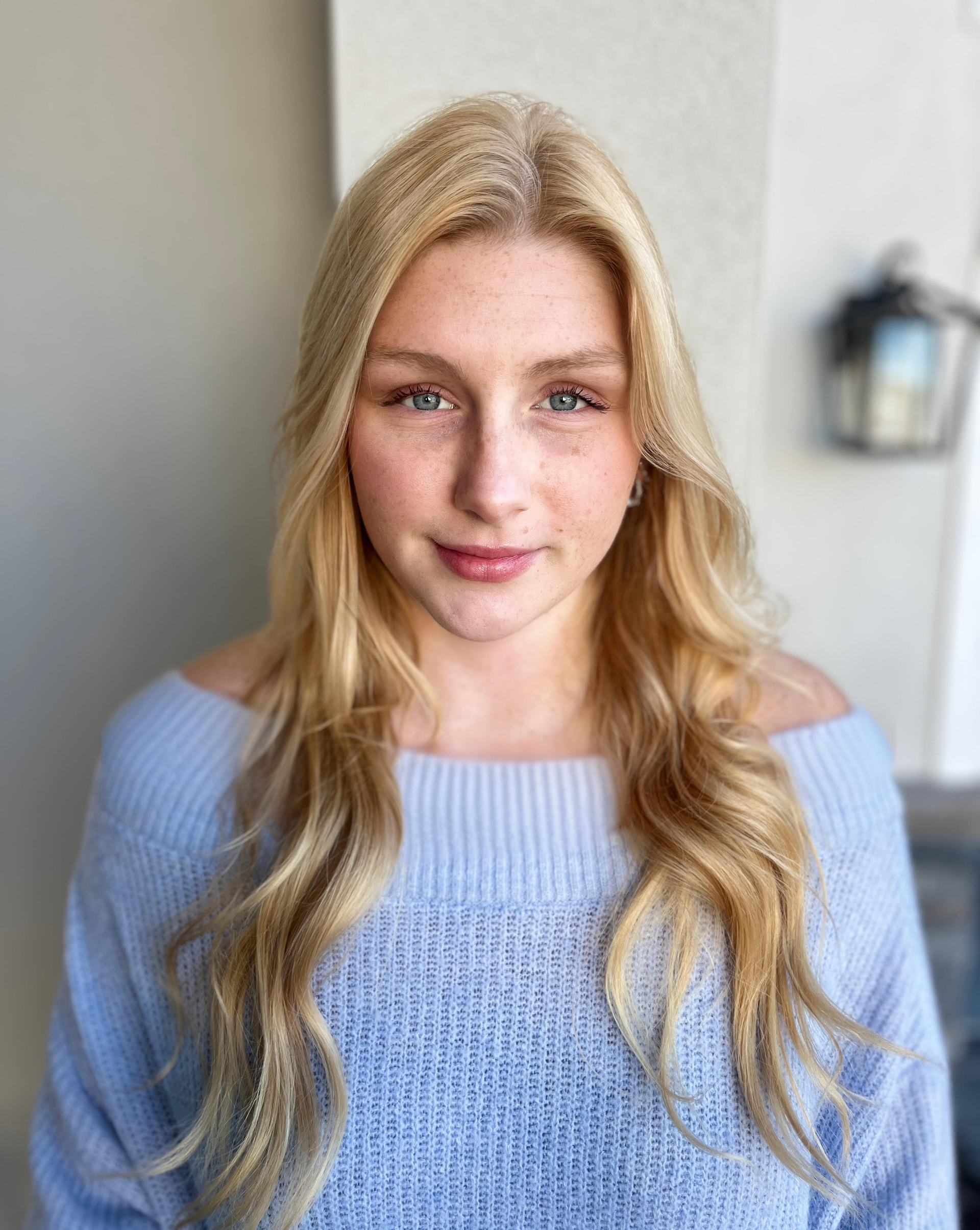 Blonde woman in a light blue sweater, looking at the camera.