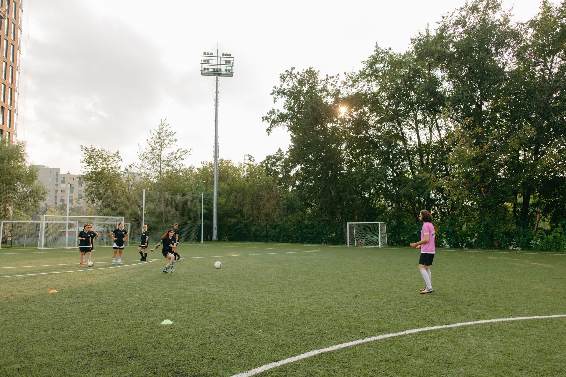 Soccer goalkeeper in black jersey number 99 stands behind the net, watching play on the field.