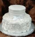 A white wedding cake with roses on it is sitting on a table.