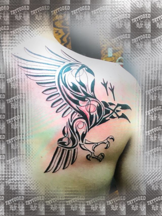 A man has a tattoo of an eagle on his back
