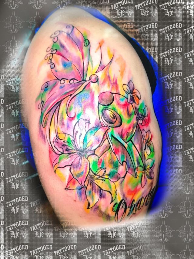 A woman has a colorful tattoo of a fairy with a butterfly on her thigh.