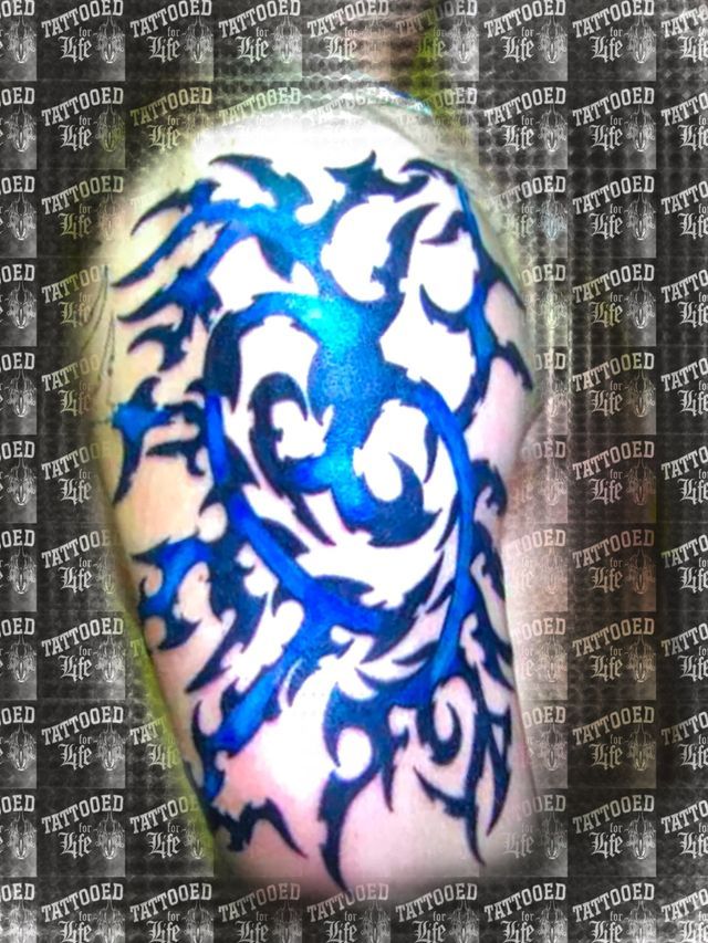 A person has a blue and white tribal tattoo on their arm