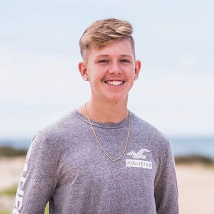 teenage patient, wearing gold chain and grey shirt, smiling