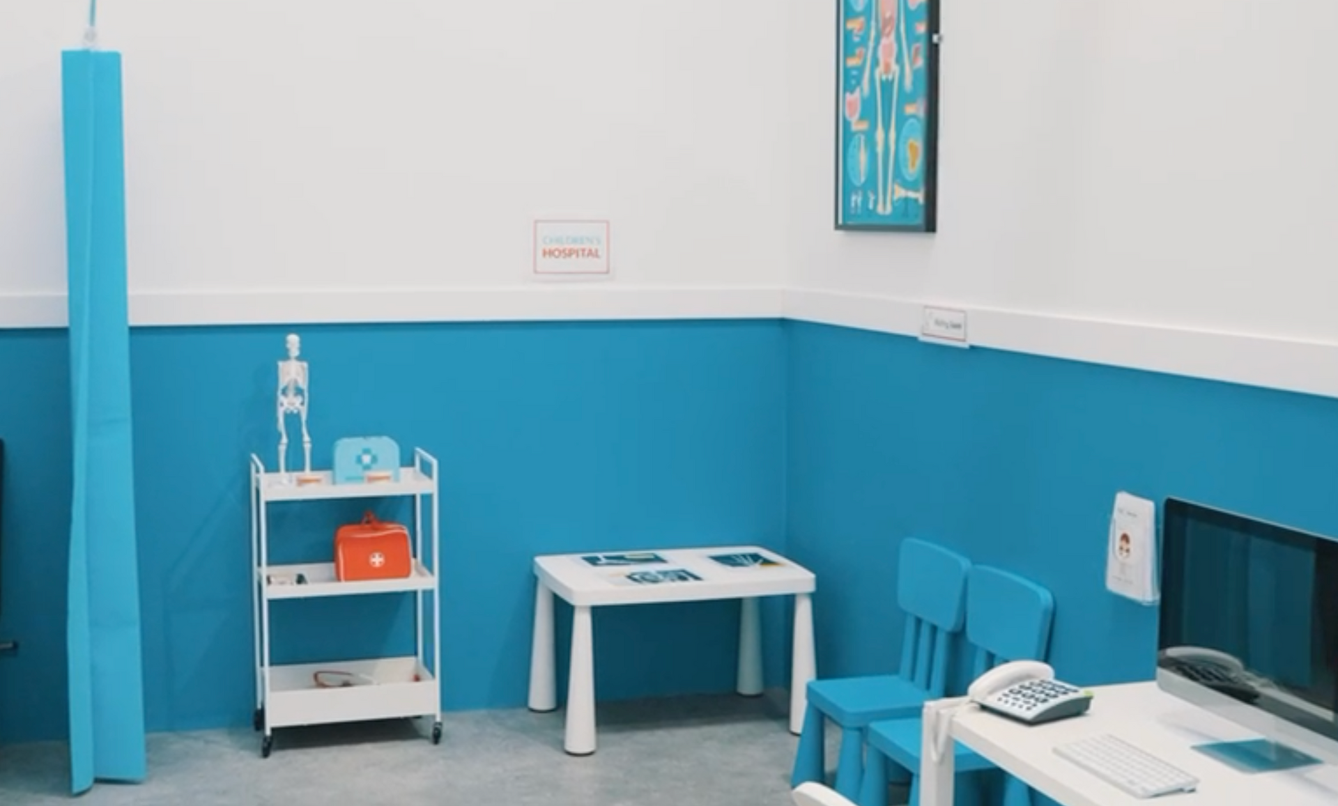 A blue and white room with a table , chairs and a computer.
