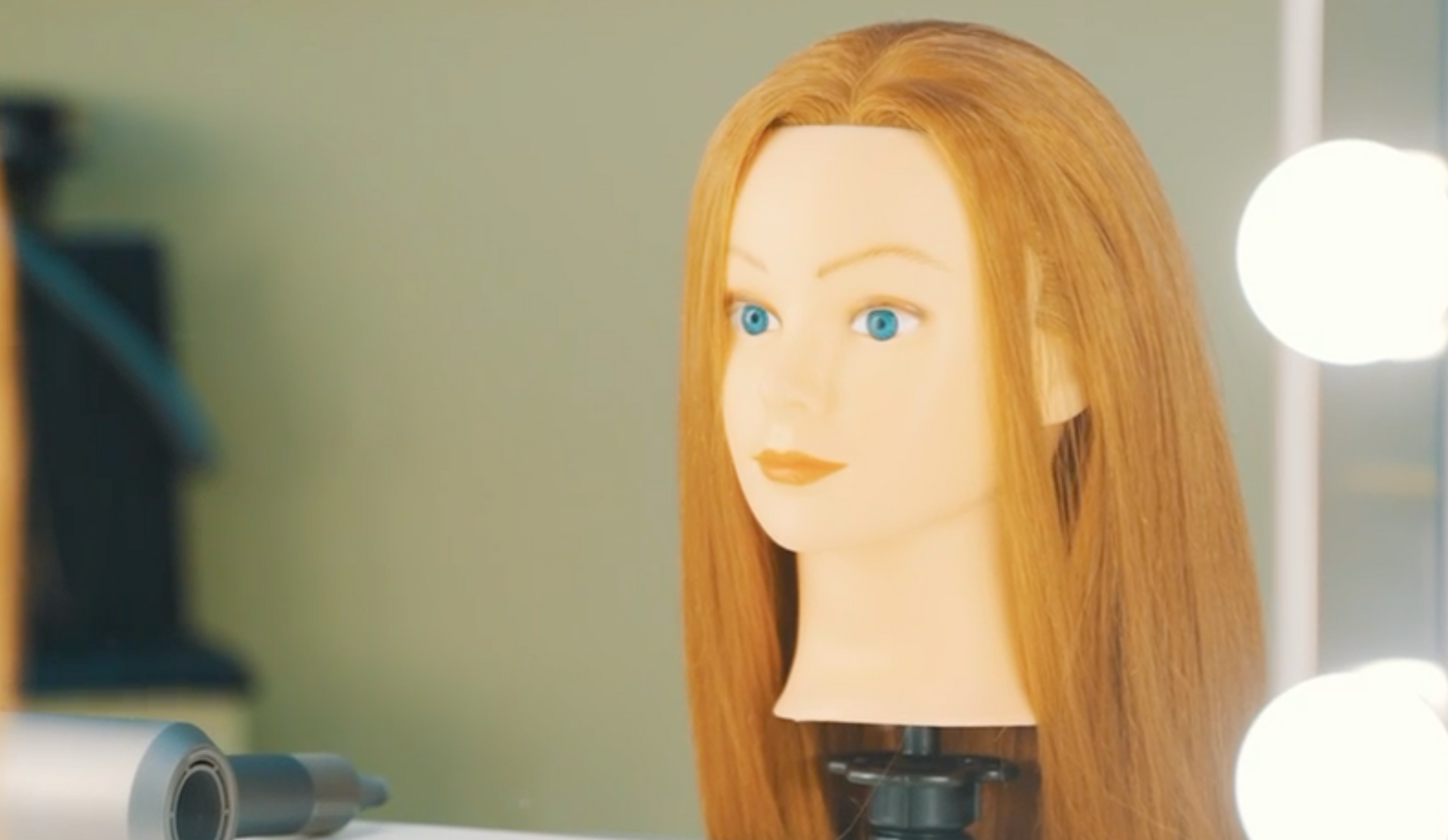 A mannequin head with long red hair is sitting in front of a mirror.